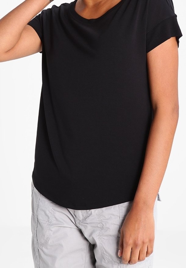 Svart kortärmad t-shirt med rund halsringning, mjukt tyg och en lätt rundad nederkant, bärs tillsammans med grå texturerade byxor.