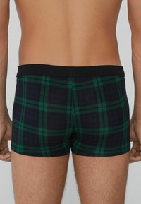 Boxershorts im grün-blauen Karomuster mit einem schwarzen elastischen Bund, ausgestattet mit einem körpernahen Schnitt und weicher Stofftextur.