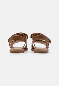 Brune sandaler med to brede stropper bak og en åpen design. Teksturerte såler og flat gummisåle med subtile sømdetaljer.