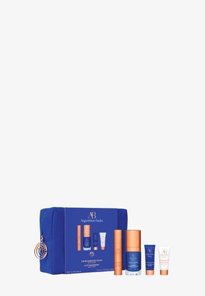 Ensemble de quatre produits de soin de la peau Augustinus Bader dans un emballage bleu et orange avec une trousse de maquillage bleue assortie.