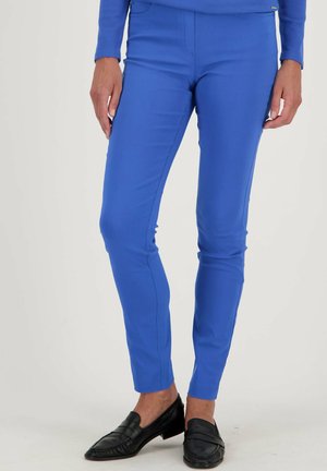 Pantalons de sport bleus à coupe slim, avec un devant plat, une texture lisse et une taille standard. Assortis à des mocassins noirs.