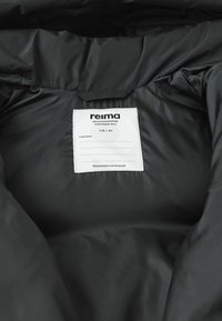 Schwarze gepolsterte Jacke mit Innenansicht, die ein weißes eingenähtes Etikett zeigt mit "Reima wetterfest seit 1944" und Größe 128 / 8Y.