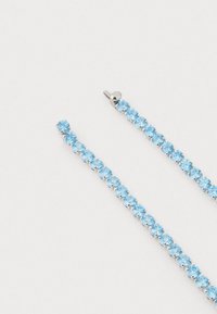 Brincos de cristal azul montados em metal prateado, apresentando um design linear com pedras redondas dispostas em uma fila contínua.