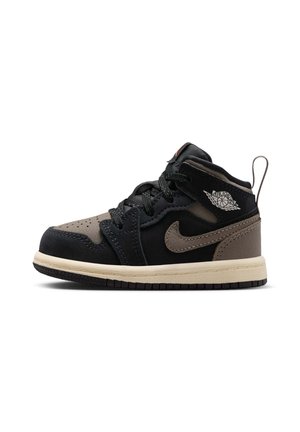 Sort og brun Air Jordan mid-top sneaker med Nike-swoosh, wings-logo, sorte snørebånd og beige sål, set fra højre mod en hvid baggrund.