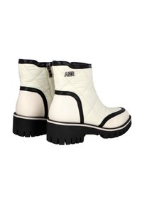Botas tobilleras acolchadas blancas con acentos negros, que cuentan con un zipper lateral, cuero texturizado y una suela de goma negra y gruesa.