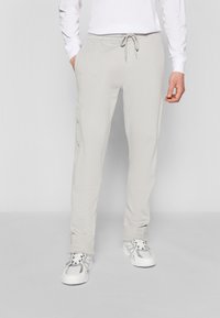 Light gray sweatpants made of soft fabric, featuring a drawstring waist, side pockets, and button details on the legs.