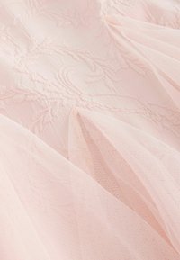 Weicher rosa Tüllstoff, übereinander gelegt auf zarter Blumen-Spitze mit aufwendigen, erhabenen Stickmustern.