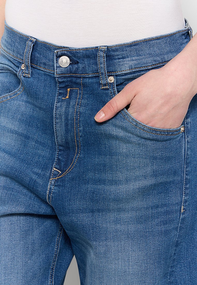 Blaue Jeans aus Denim mit mittlerem Bund, ausgestattet mit einem Knopfverschluss, Gürtelschlaufen und einer vorderen Tasche mit kontrastierendem Stickdetail.