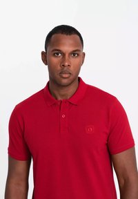 Röd polo skjorta i bomull med klassisk krage, korta ärmar och en subtil broderad logotyp på bröstet.