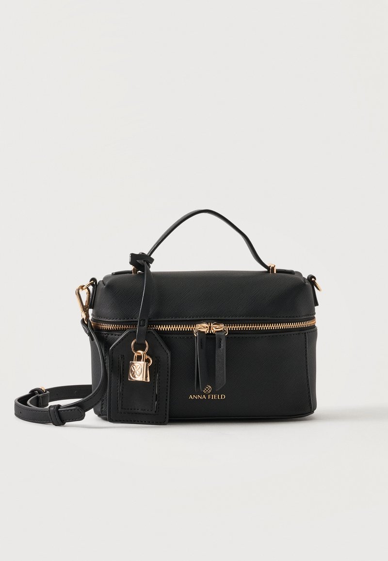 Sac à main rectangulaire noir avec fermeture éclair dorée, poignée supérieure, bandoulière amovible et petit cadenas doré sur l'étiquette de marque à l'avant.