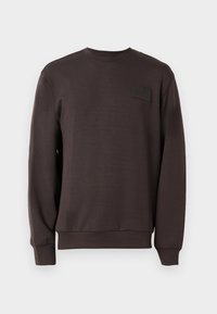 Mørkebrun crewneck sweatshirt laget av mykt stoff. Har et teksturert rektangulært patch på brystet, samt ribbestrikkede ermer og nederkant.
