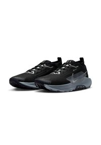Zapatillas deportivas negras con parte superior de malla, superficie texturizada y una suela gris translúcida. Presentan un distintivo logo de swoosh y sistema de cordones.