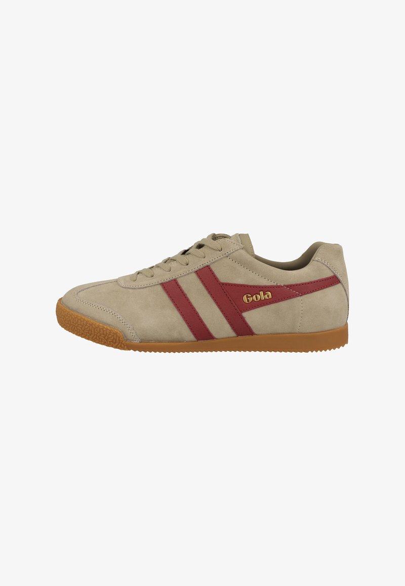 Zapatilla deportiva de ante beige con suela marrón, rayas laterales rojas y logotipo "Gola" en dorado en el lado exterior, de corte bajo con cordones.