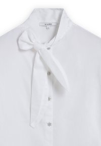 Weiße Bluse mit einem Schleifenkragen, verziert mit dekorativen silbernen Knöpfen und einer glatten Textur. Das Etikett trägt die Aufschrift "SCALPERS", Größe S.