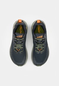 Trail løbesko med en mørk navy overdel, grønne snørebånd, orange detaljer, strukturerede mønstre og en polstret sål til udendørs præstation.