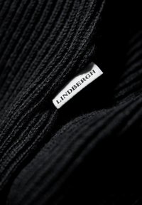 Zwart gebreid stof met ribbelstructuur; etiket leest "Lindbergh" in wit op een zwarte achtergrond.