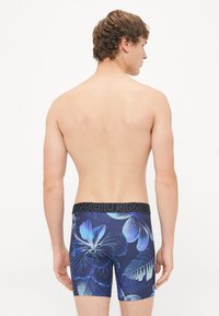 Boxeri pentru bărbați cu un model floral bleu închis, cu designuri de hibiscus și frunze, un brâu elastic negru cu logo-ul brandului.