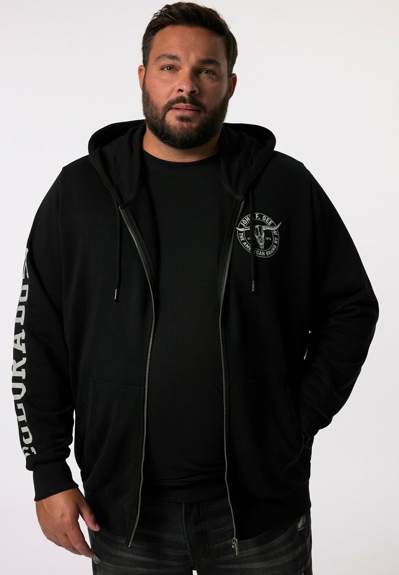Sudadera negra con cremallera, capucha con cordón, bolsillos laterales y un logo circular en el pecho. Presenta texto blanco a lo largo de una manga.