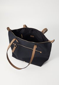 Svart tygväska med bruna läderremmar och detaljer. Har en dragkedjeficka på framsidan och ett rymligt inre.