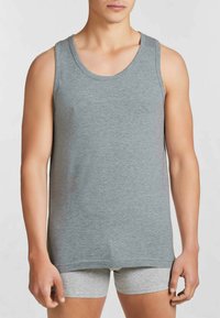 Top in cotone grigio senza maniche con scollatura rotonda e ampie spalline, caratterizzato da una vestibilità comoda e una superficie liscia. Indossato sopra slip grigi.