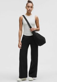 Top grigio senza maniche, pantaloni neri a gamba larga e una borsa a tracolla nera. Tessuto liscio, vestibilità comoda e design minimalista.