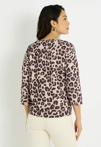 Suéter pullover de estampado de leopardo en beige y púrpura oscuro, con un corte relajado, mangas de tres cuartos y un tejido texturizado.