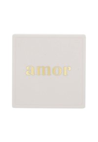 Vit rektangulär bricka med guldfolierad text "amor" centrerad på ytan.