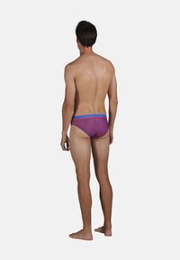 Slips de bain pour hommes en violet avec des rayures horizontales rouges, dotés d'une taille élastique bleue et d'une coupe ajustée.