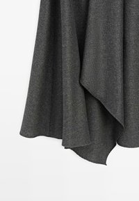 Tissu en laine gris foncé avec un tombé souple suspendu, montrant un tissage texturé et des bords superposés sur un fond blanc.