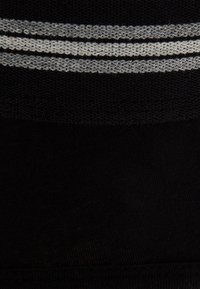 Sezione di tessuto nero con una parte superiore in maglia testurizzata caratterizzata da tre strisce orizzontali grigie. Parte inferiore liscia, uniforme nel colore.