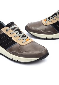 Baskets en cuir marron et textile avec une languette en suède beige, des rayures noires, des lacets gris et un intercalaire blanc texturé. Présente un accent orange.