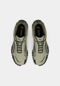 Khakifarbene Sportschuhe mit einem strukturierten Obermaterial, schwarzem, robustem Profil und Schnürdesign. Verfügt über eine Ortholite-Einlage für zusätzlichen Komfort.