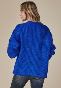 Lässig geschnittenen blauer Strickpullover mit vertikaler Rippstruktur, rundem Ausschnitt und überschnittenen Schultern. Texturierter Stoff und weite Ärmel.