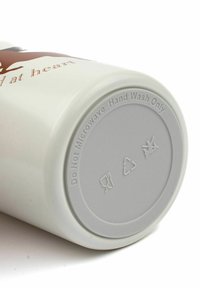 Keramični lonček z belo zunanjostjo in rjavim napisom. Okrogla oblika z gladko teksturo; dno vsebuje navodila za nego in simbole za recikliranje.