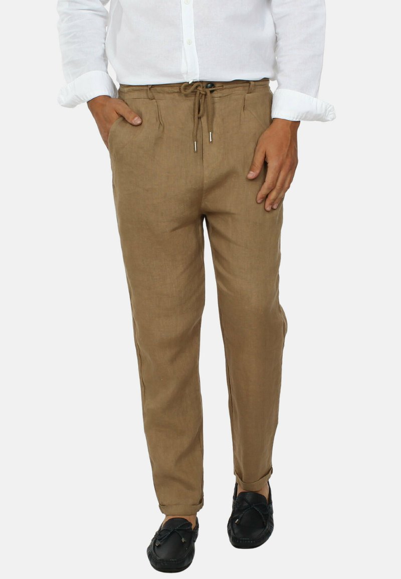 Pantaloni in lino beige con vita elastica e cordoncino, dotati di tasche laterali e vestibilità rilassata, abbinati a mocassini neri.