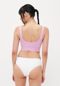 Ljubičasti crop top s širokim naramenicama i izrezom na leđima, uparen s bijelim gaćicama visokog struka. Glatka tekstura, minimalistički dizajn.