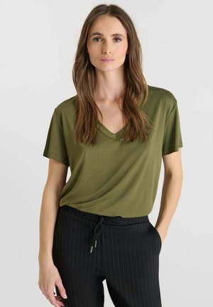 Olivgrünes V-Ausschnitt T-Shirt aus glattem Stoff, mit kurzen Ärmeln und lockerer Passform, kombiniert mit schwarz gestreiften Hosen.