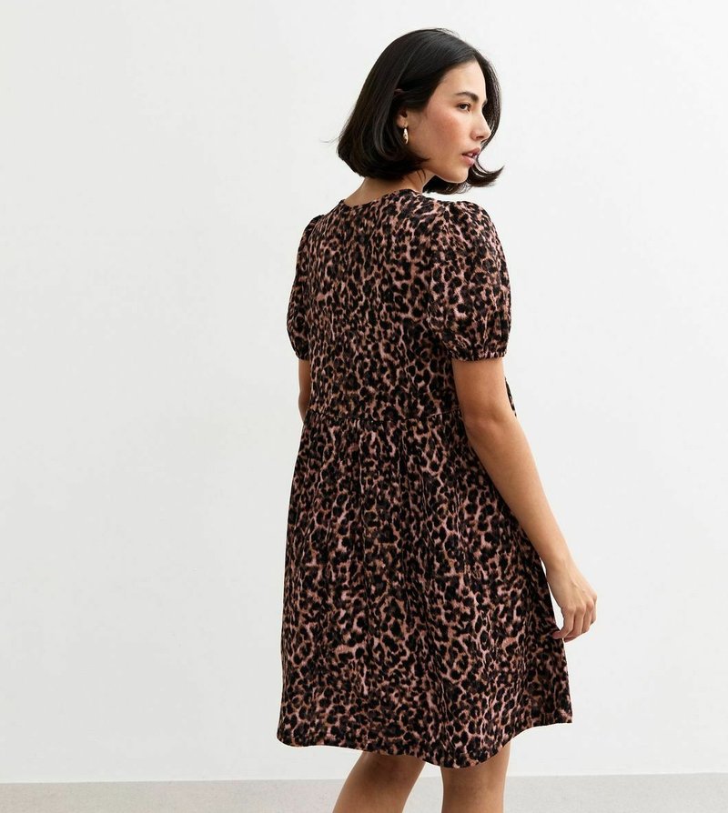 Vestito con fantasia leopardata in marrone e nero, lunghezza al ginocchio, maniche a sbuffo corte, vita arricciata, tessuto morbido, con scollatura rotonda e dettaglio sulla schiena.