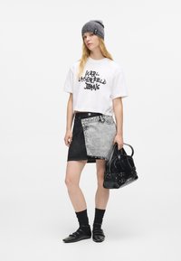 Balta trumpa marškinėliai su juodu tekstu, juoda ir pilka džinsinė sijonas, juoda rankinė, juodos kojinės ir juodi batai. Pilka mezgimo beanie.