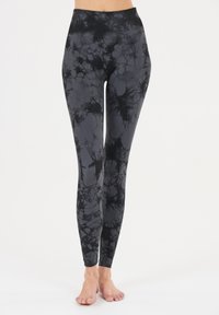 Leggings en tie-dye noir et gris fabriqués en tissu extensible ; dotés d'une taille haute et d'un design long avec une texture lisse.