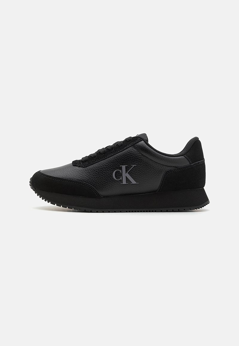 Juodas sportinis sneakeris pagamintas iš odos ir daimio medžiagų, su tekstūruotu paviršiumi, apvalia nosimi, raišteliais ir subtiliu logotipo akcentu.