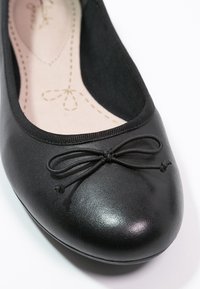 Ballerines en cuir noir avec bout arrondi, bord en tissu et accent de nœud décoratif sur le bout. Texture lisse et design minimaliste.