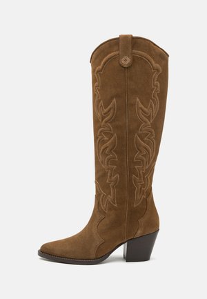 Brązowe zamszowe botki do kolan z wąskim czubkiem, na słupku, ozdobione dekoracyjnym przeszyciem w stylu western wzdłuż cholewki.