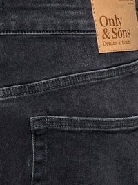 Détail de la poche arrière d'un jean en denim noir avec des coutures apparentes et une étiquette en cuir beige indiquant Only & Sons Denim artisans.
