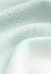 Tessuto di cotone azzurro chiaro con una superficie liscia, che presenta sottili motivi a maglia e leggere ondulazioni.