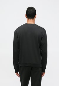 Μαύρη μπλο�ύζα με στρογγυλή λαιμόκοψη, μακριά μανίκια και άνετη εφαρμογή. Διαθέτει ριχτούς μανσέτες και στρίφωμα, λεία υφή και μινιμαλιστικό σχέδιο.