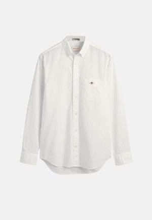 Camicia bianca classica in cotone, con taschino sul petto e un piccolo logo. Maniche lunghe e orlo leggermente arrotondato.