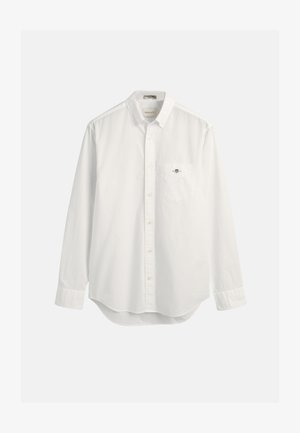 Hvit skjorte med knapper laget av bomull, med en brystlomme og en liten logo. Langermet og med en lett avrundet nederkant.
