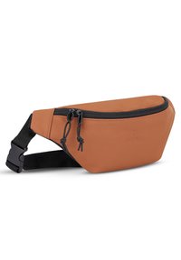 Bælletaske i tanfarvet læder med sort justerbar rem og dobbelte lynlåslukninger på hvid baggrund.