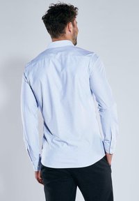 Langarmhemd in hellblau und weißen Streifen, aus Baumwolle gefertigt. Verfügt über einen Kentkragen und geknöpfte Manschetten, mit einem geraden Schnitt am Rücken.